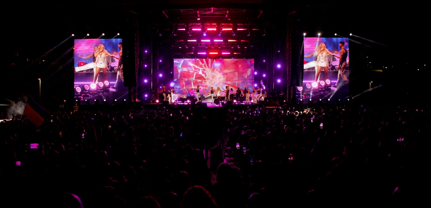 Mariah Carey on the giant IMAG side screens at LA Pride in the Park, arms outstretched, the multi-surface LED stage glowing pink and purple over the crowd.